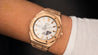 Montre de face g-shock or rose bracelet full metal au poignet d'un homme sur un fond unie de couleur noir 